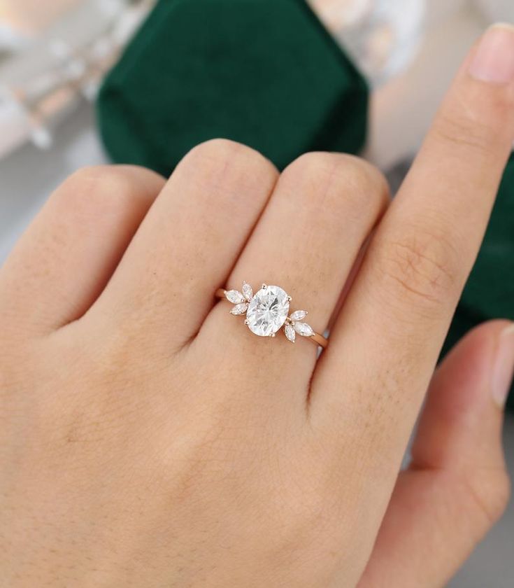 a woman's hand holding an engagement ring with two diamonds on the top and bottom