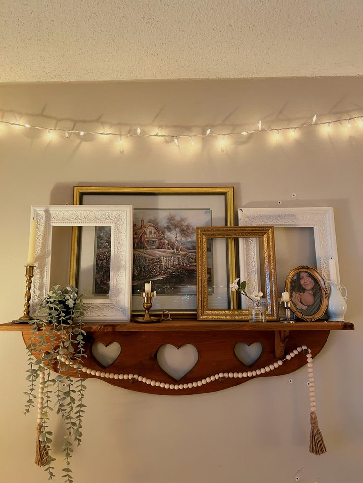 there is a shelf with pictures on it and lights strung over the wall behind it