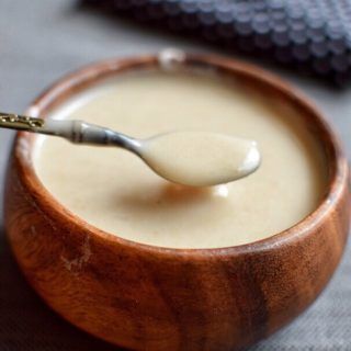 a spoon in a wooden bowl filled with cream