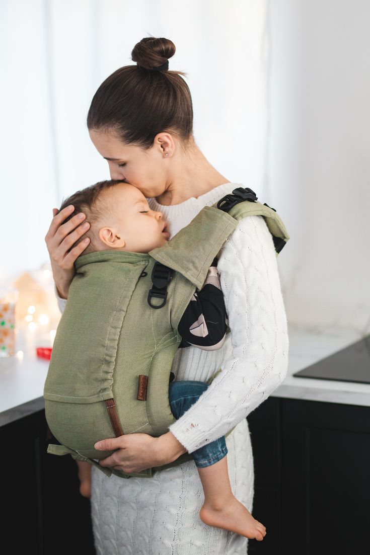 a woman is holding a baby in a sling and it's face to her chest