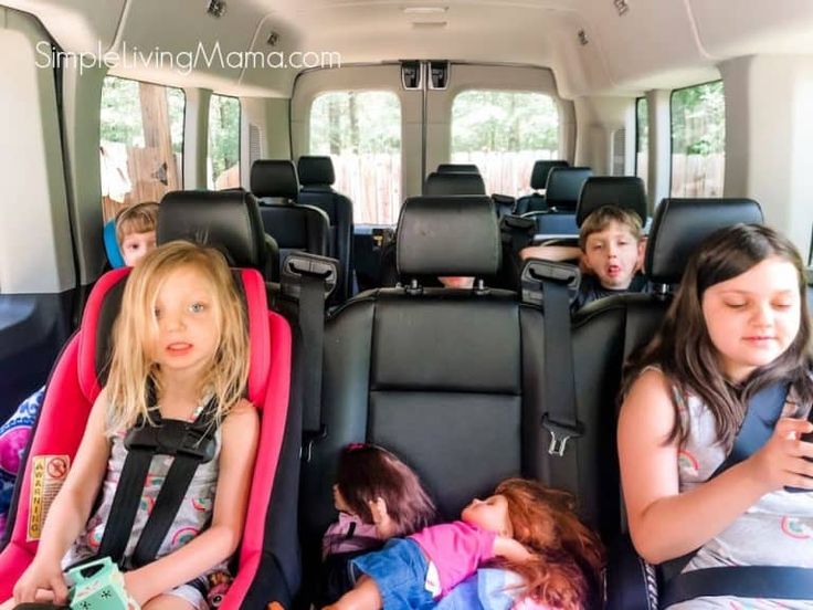 three children sitting in the back of a van with their phones up to their ears