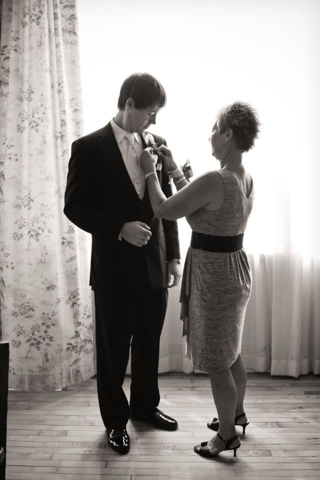 a man and woman standing next to each other in front of a window with curtains