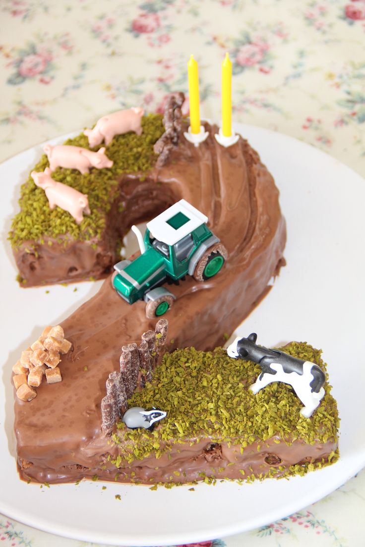 a birthday cake with a tractor and farm animals on it, sitting on a plate