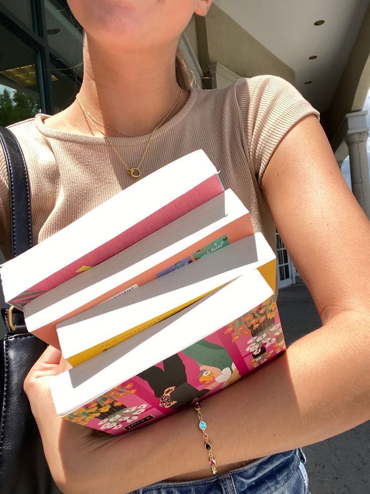 a woman holding a stack of books in her hands