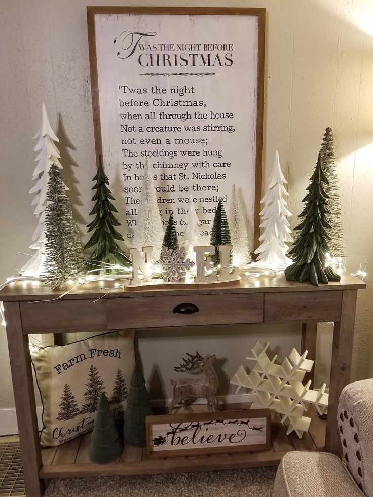 a table with christmas trees and lights on it in front of a sign that reads, the night before christmas