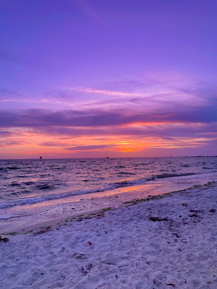 the sun is setting over the ocean on the beach