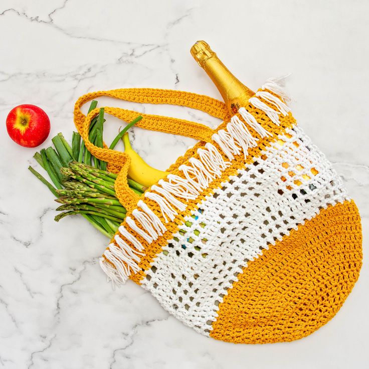 a yellow and white bag with fruit on it next to an orange, red apple