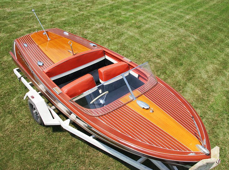 an orange and brown boat on trailer in grass