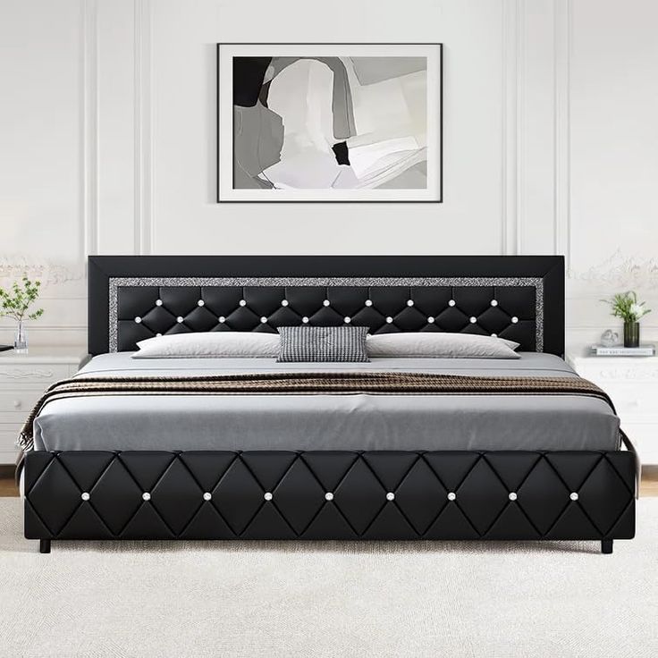 a large bed with black leather headboard and foot board in a white walled room