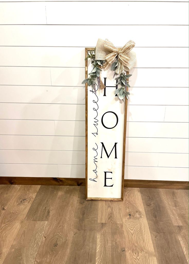 a wooden sign that says home is where the heart is and leaves are on it