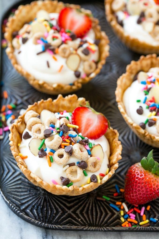 several desserts are sitting on a tray with sprinkles and strawberries