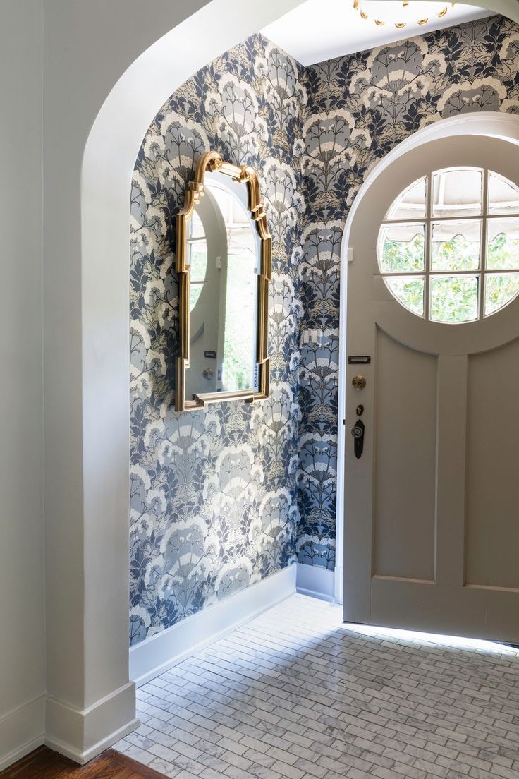 an arched doorway leads to a hallway with blue and white wallpaper