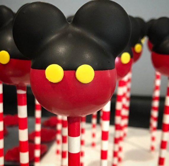 mickey mouse lollipops are lined up on red and white striped sticks