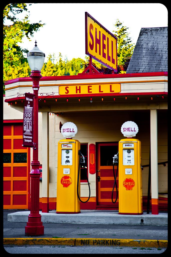 two yellow shell gas pumps sitting in front of a red and white building with a sign that says shell