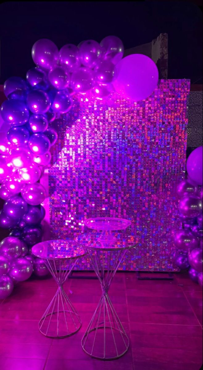 purple and silver balloons are on display in front of a wall with sequins