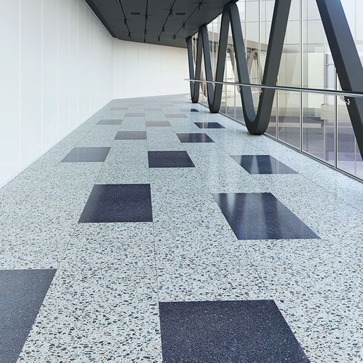 an empty room with black and white tiles on the floor next to a building wall