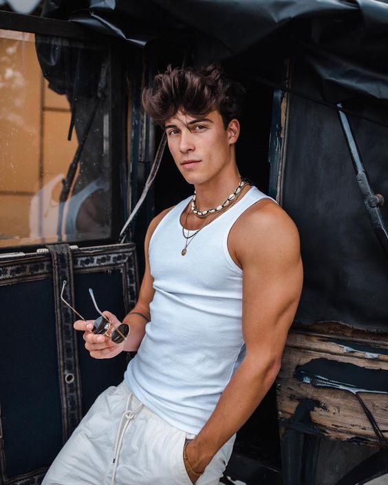 a man in white shirt holding a cellphone next to an old truck with doors open