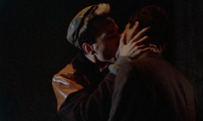 two people are kissing in the dark with their hands on each other's shoulders