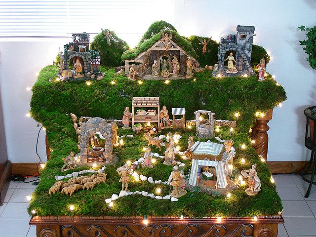 a nativity scene is displayed on top of a table with christmas lights and decorations