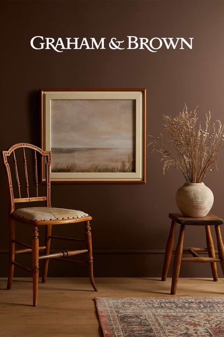 two chairs and a vase in front of a wall with the words graham & brown on it