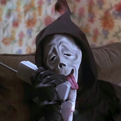 a person wearing a mask and holding a cell phone to their face while sitting on a couch