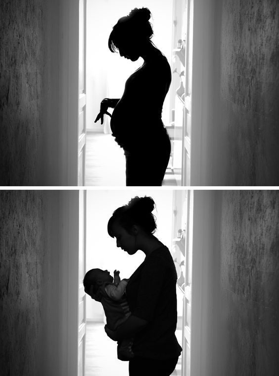 a woman holding a baby in her arms while standing next to an open door with the light coming through