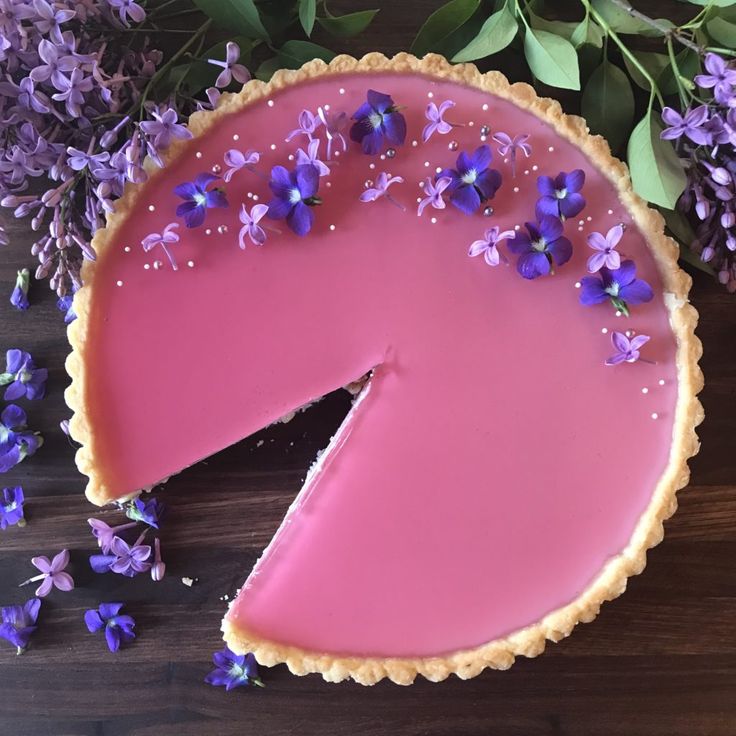 a pink pie with purple flowers on the side