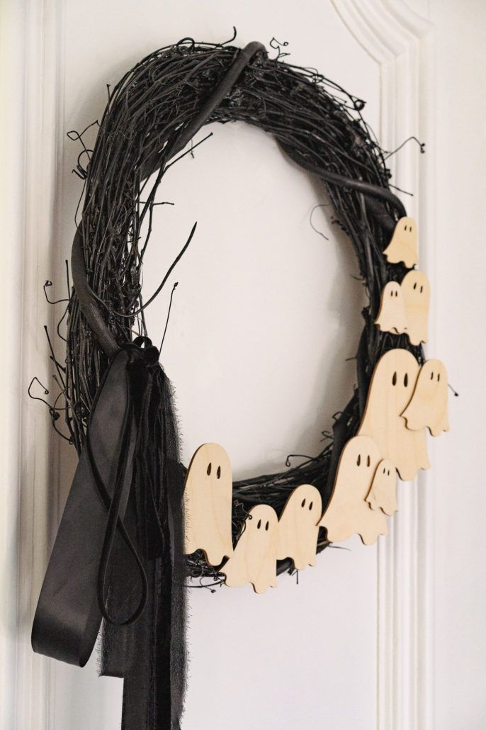 a wreath with ghost decorations hanging on the front door