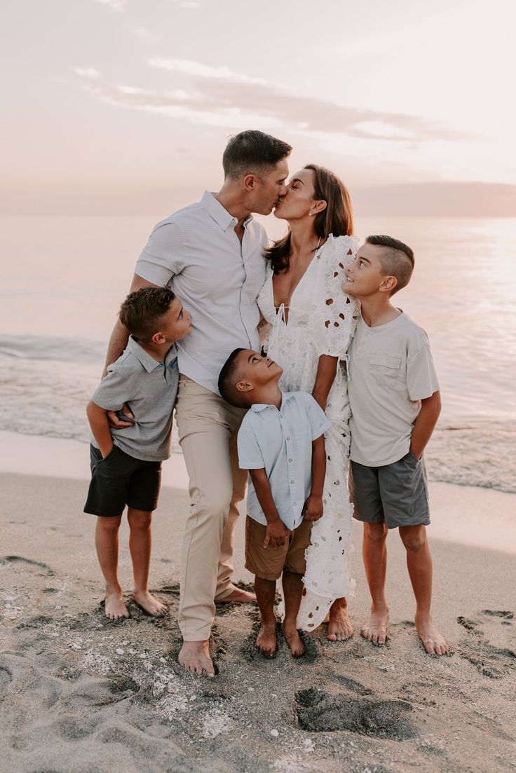 a family kissing on the beach at sunset