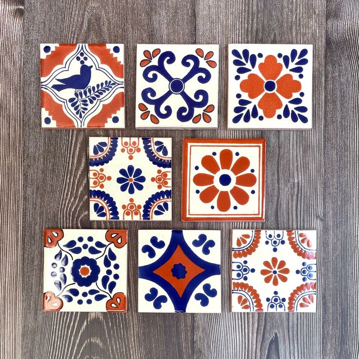 colorful tiles are arranged on a wooden surface, including one with an orange and blue design