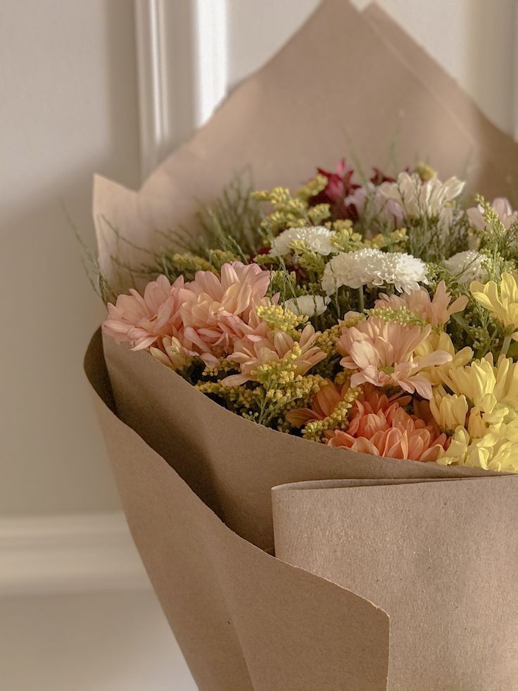 a bouquet of flowers is wrapped in brown paper