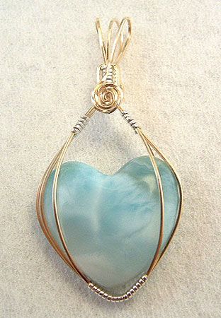 a heart shaped glass pendant with wire wrapped around it