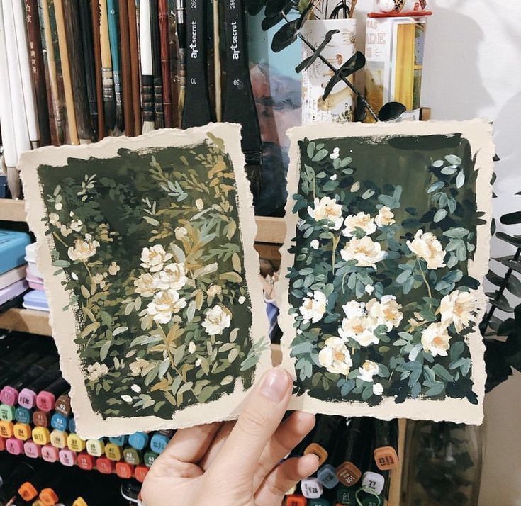 someone holding up two pictures with flowers on them