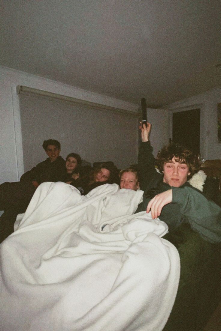 a group of people sitting on couches in a living room with blankets over them