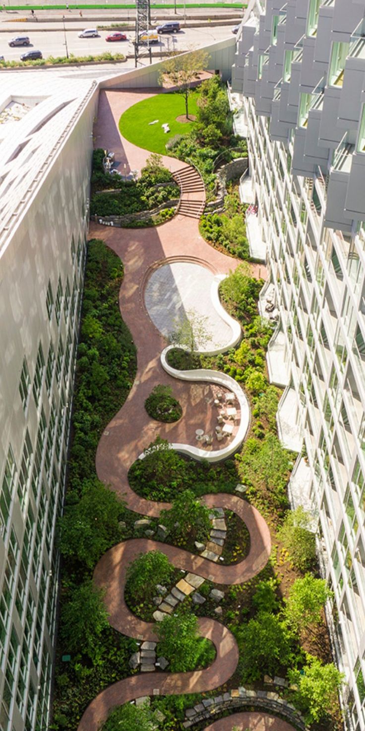 an aerial view of a courtyard and garden in the middle of two buildings, with trees on both sides