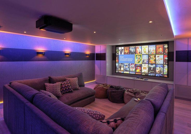 a large couch sitting in front of a flat screen tv inside of a home theater