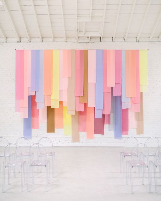 a room filled with lots of chairs covered in colorful sheets of paper hanging from the ceiling