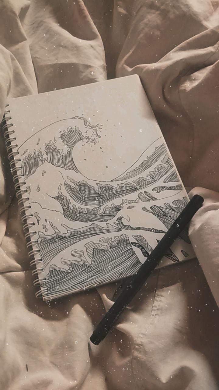 an open notebook with a drawing of a wave on it and a pen laying next to it