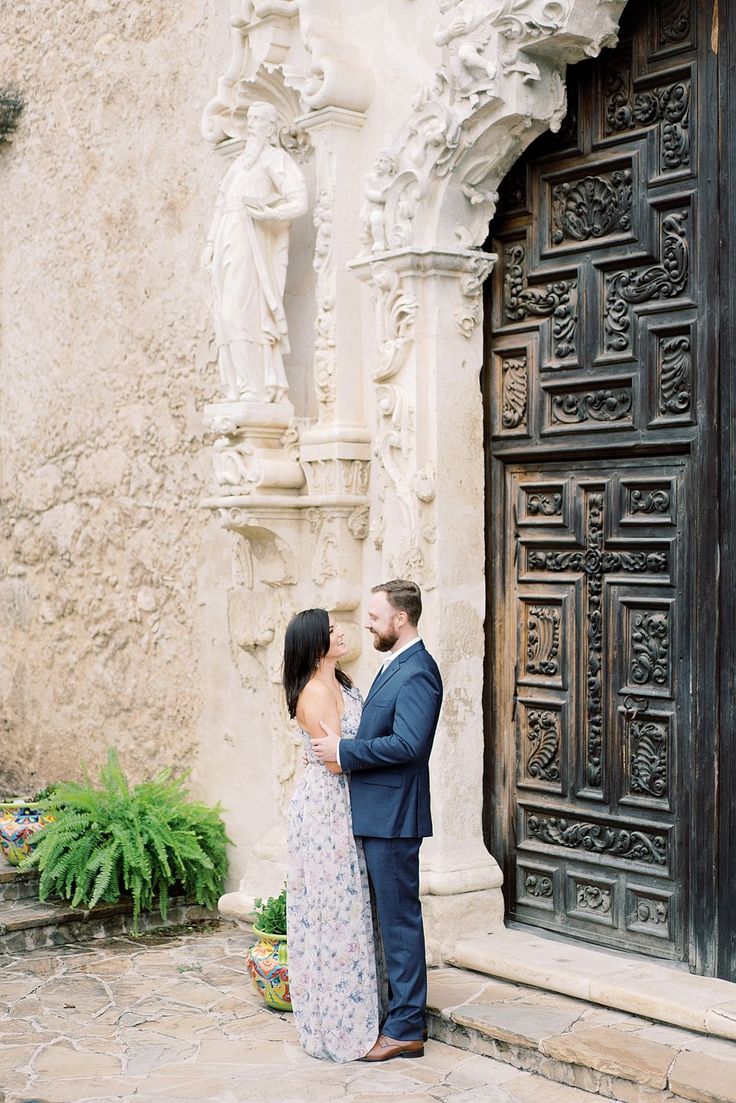 a man and woman standing next to each other in front of an ornate wooden door