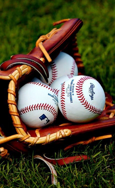 three baseballs in a catchers mitt on the grass