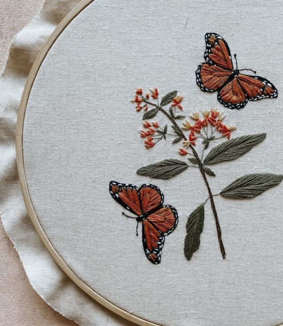 three orange butterflies sitting on top of a white piece of cloth next to a flower