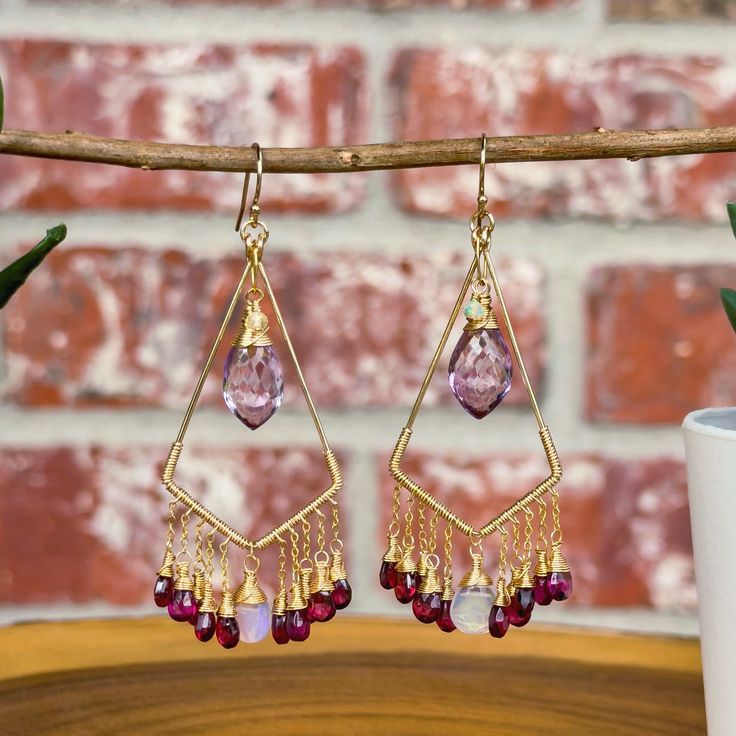 Introducing these boho chic chandelier earrings, which combine an array of magical gemstones and combination of colors.  These earrings are created using hand-forged 14k gold filled earring frames. Each earring is adorned individually wire wrapped Rhodolite Garnets and Ethiopian Opals that sway from the bottom of the gold frames. Large stunning AAA pink Amethyst hang front in center making them the main focal of these earrings.  Click here to see our full line of handmade gemstone earrings: http Bohemian Gold Crystal Earrings With Gemstone, Gold Bohemian Crystal Gemstone Earrings, Bohemian Amethyst Chandelier Earrings Gift, Bohemian Gemstone Dangle Chandelier Earrings, Bohemian Gemstone Chandelier Dangle Earrings, Bohemian Gemstone Chandelier Earrings, Bohemian Purple Dangle Chandelier Earrings, Bohemian Crystal Dangle Earrings With Gemstones, Bohemian Dangle Gemstone Crystal Earrings