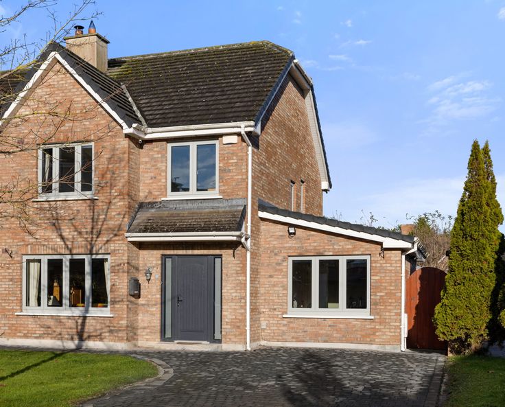 a large brick house with white trim on the windows and doors, along with a driveway