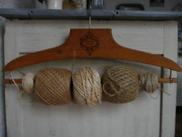 three balls of yarn are hanging from a wooden hanger on a white cabinet door