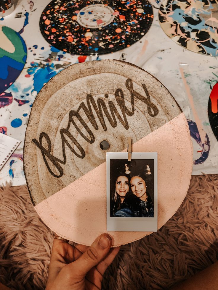 someone holding up a polaroid in front of a wall with pictures and words on it