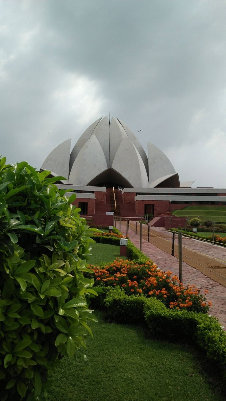 a large building with many flowers in front of it and some bushes on the other side