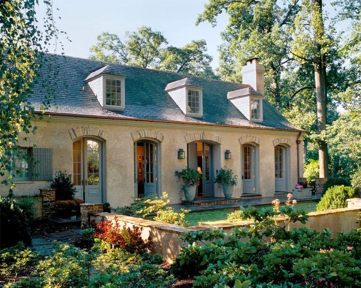 the house is surrounded by greenery and trees, with two large windows on each side