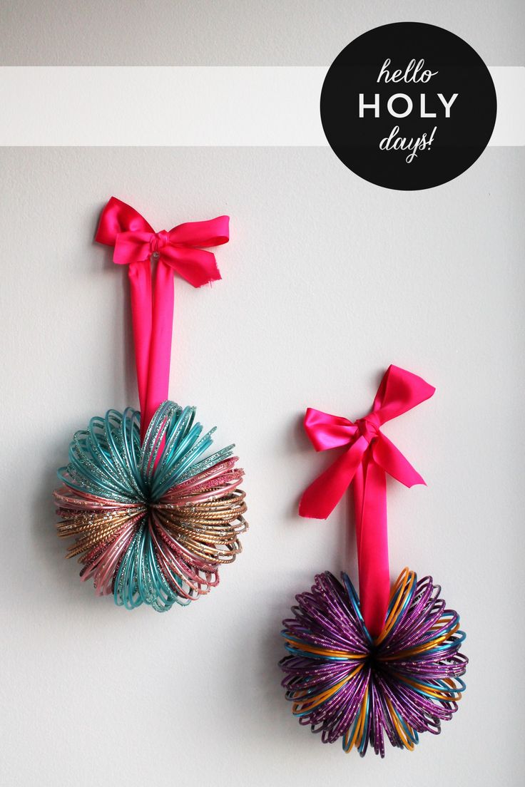 two colorful bells hanging from the side of a wall with ribbons attached to each one