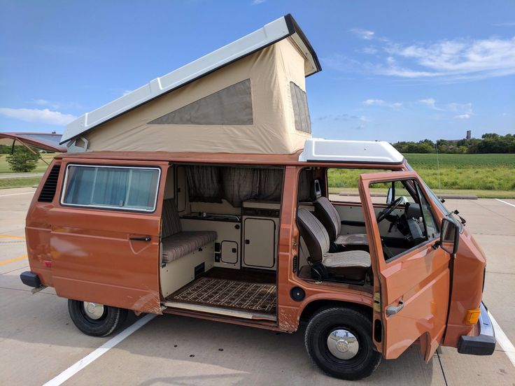 an old camper van parked in a parking lot with its doors open and the roof up