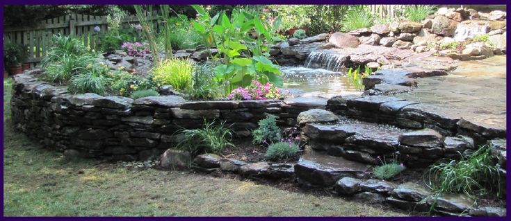 there is a small waterfall in the middle of this garden with rocks and plants growing out of it